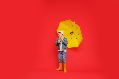 Photo of Little boy with yellow umbrella on red background