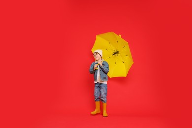 Little boy with yellow umbrella on red background