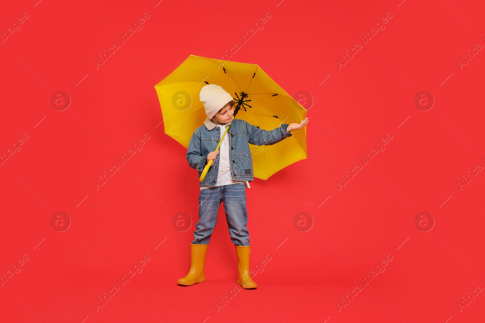 Photo of Little boy with yellow umbrella on red background