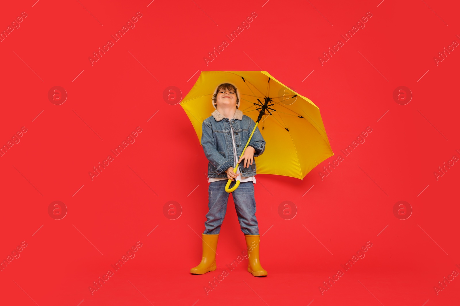 Photo of Little boy with yellow umbrella on red background