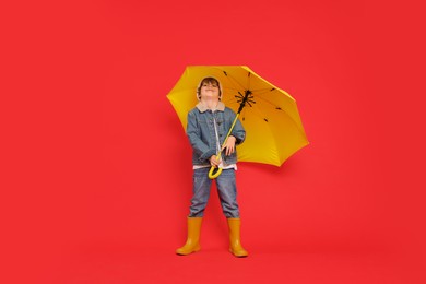 Little boy with yellow umbrella on red background