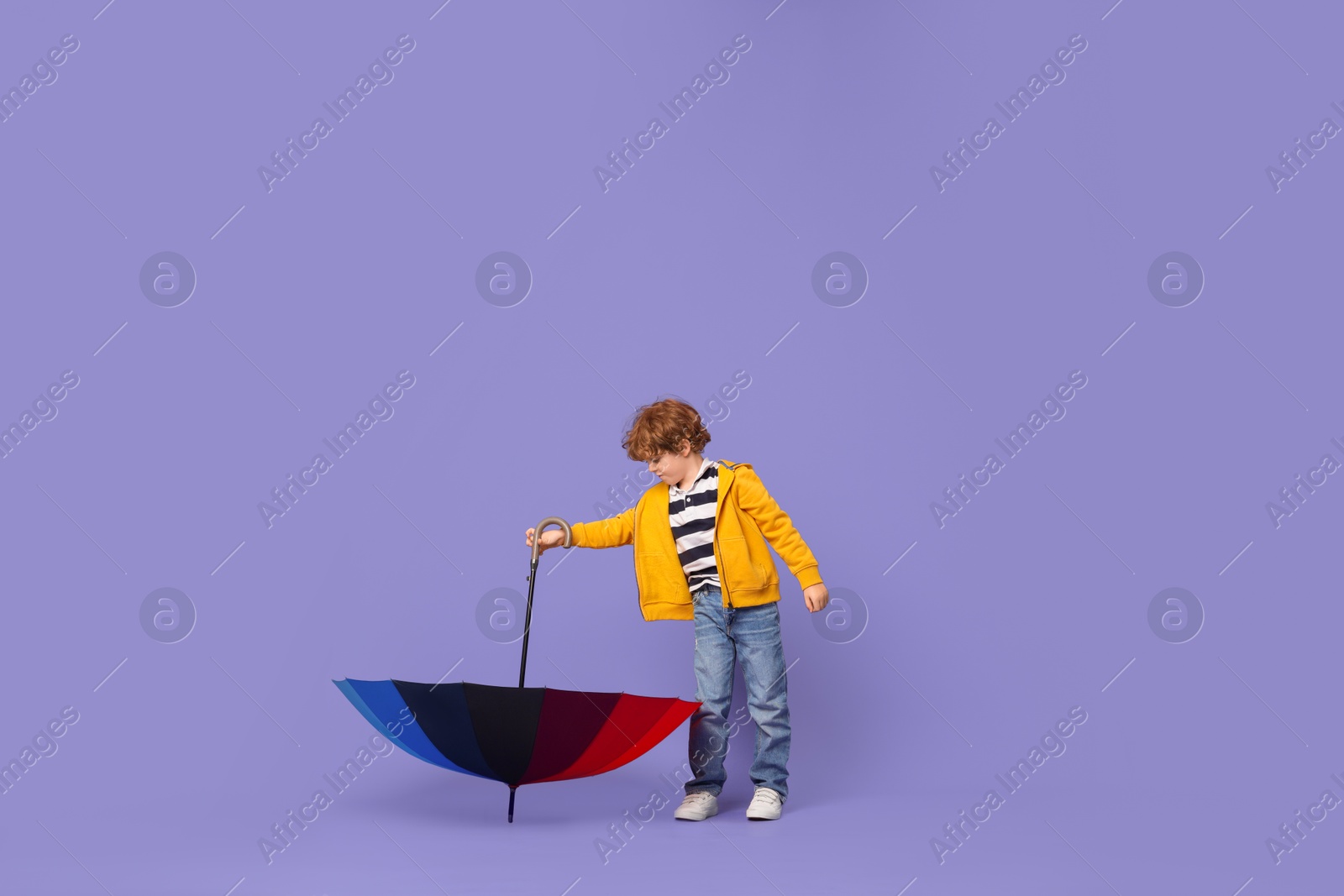 Photo of Little boy with rainbow umbrella on purple background