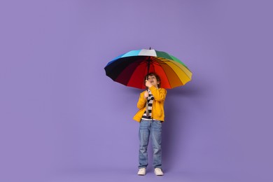 Photo of Little boy with rainbow umbrella on purple background
