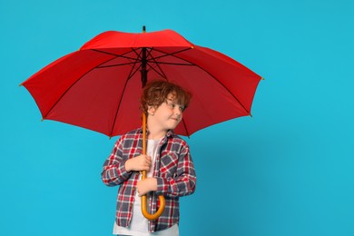 Photo of Little boy with red umbrella on light blue background
