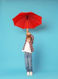 Photo of Little boy with red umbrella on light blue background