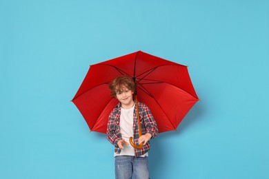 Photo of Little boy with red umbrella on light blue background