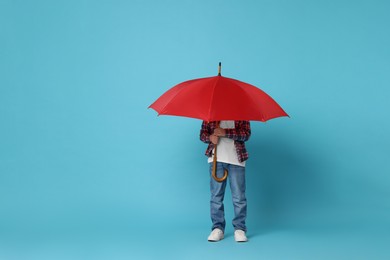 Photo of Little boy with red umbrella on light blue background