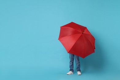 Photo of Little boy with red umbrella on light blue background, space for text