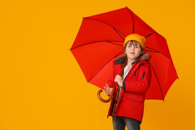 Little boy with red umbrella on orange background, space for text