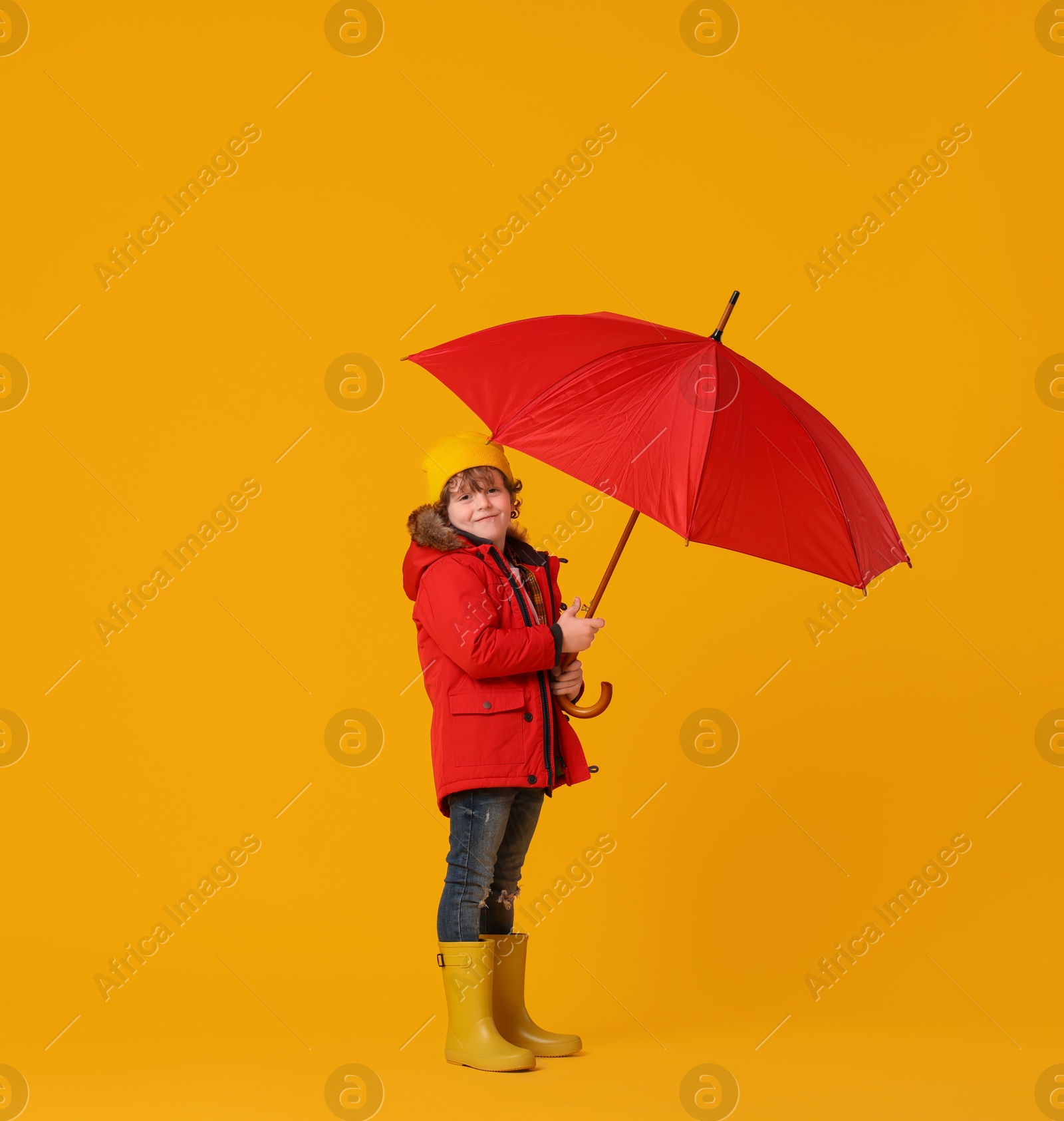 Photo of Little boy with red umbrella on orange background