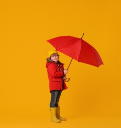 Photo of Little boy with red umbrella on orange background