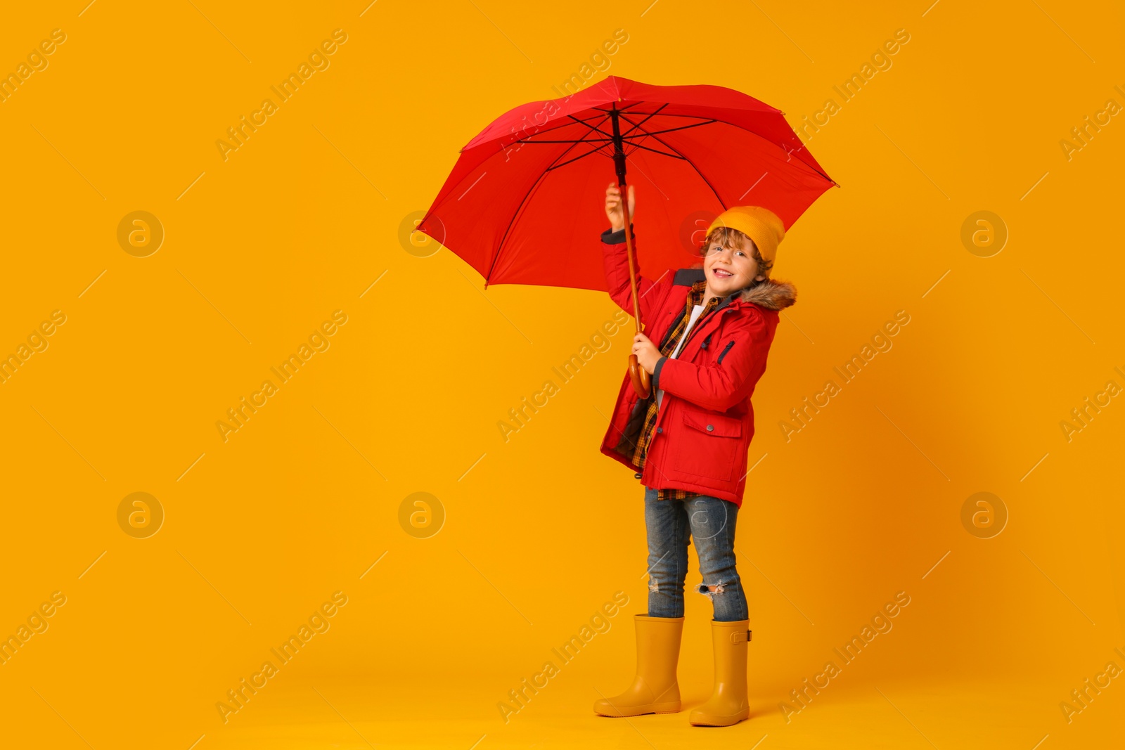 Photo of Little boy with red umbrella on orange background