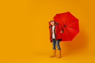 Photo of Little boy with red umbrella on orange background