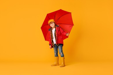 Photo of Little boy with red umbrella on orange background