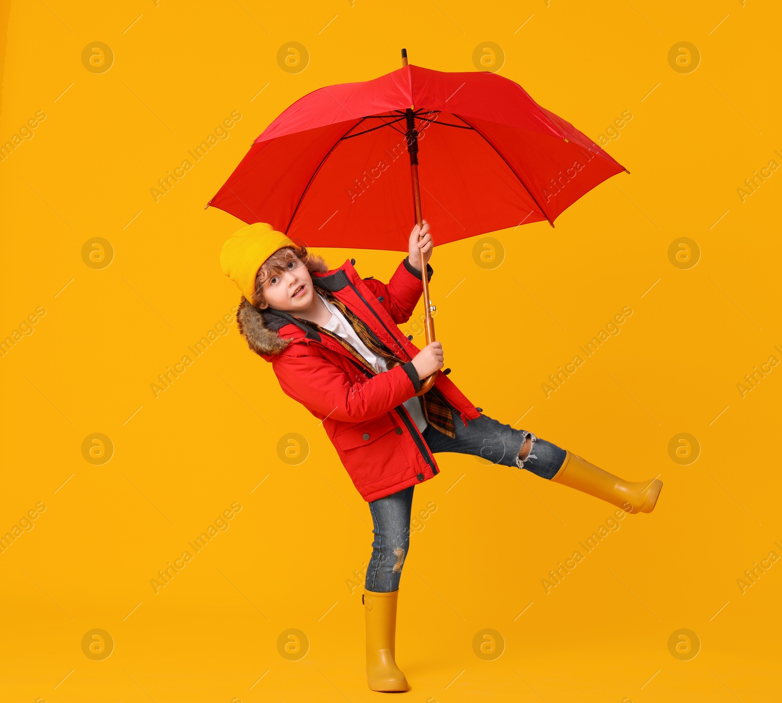 Photo of Little boy with red umbrella on orange background