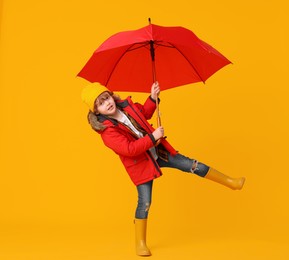 Photo of Little boy with red umbrella on orange background