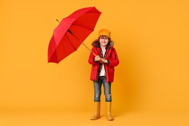 Little boy with red umbrella on orange background