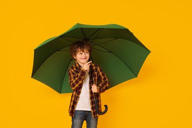 Photo of Little boy with green umbrella on orange background