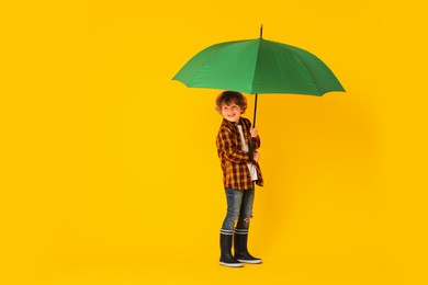 Photo of Little boy with green umbrella on orange background