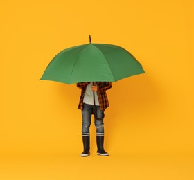 Photo of Little boy with green umbrella on orange background