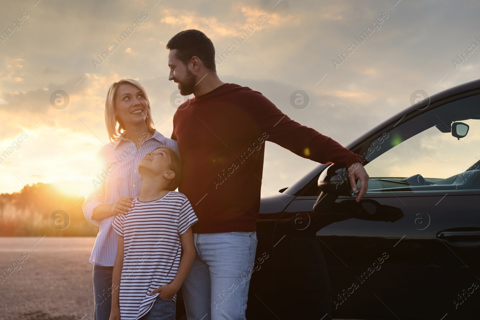 Photo of Cute family near car outdoors at sunset