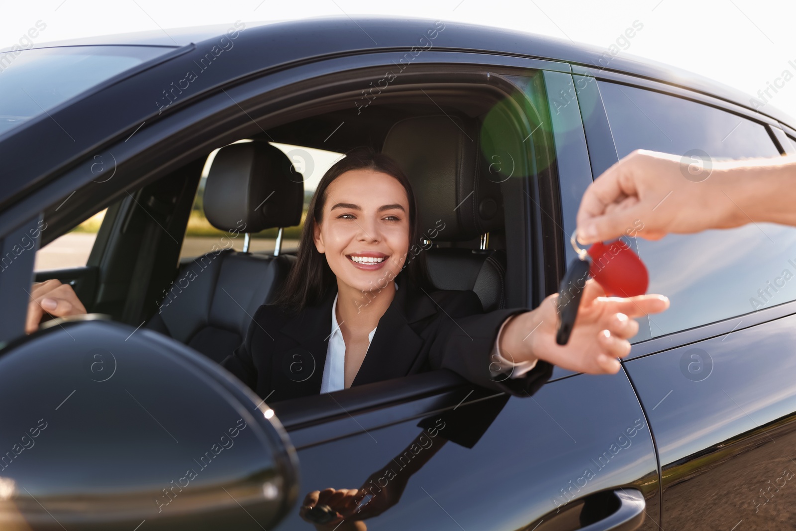 Photo of Happy young woman getting key inside her new car