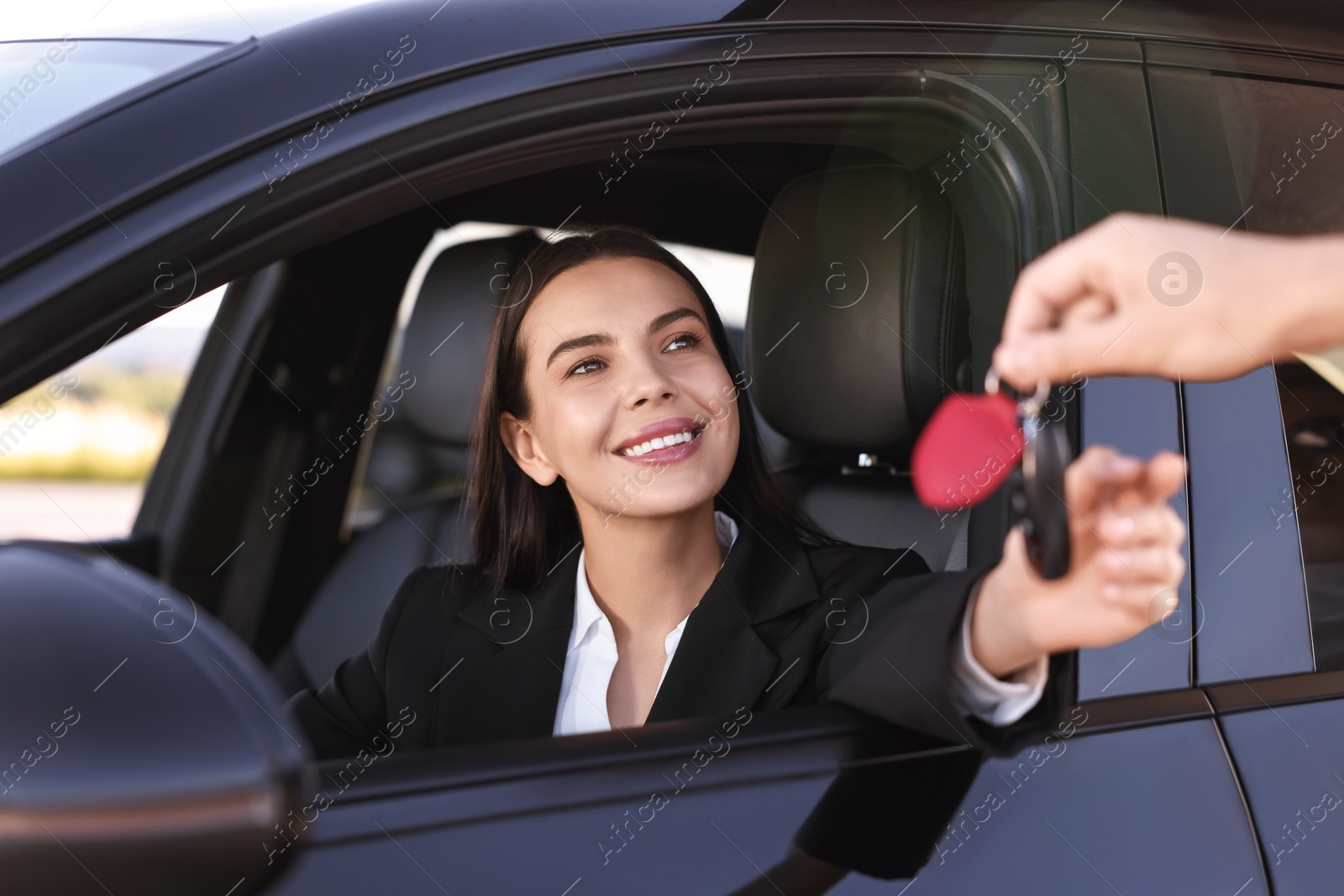 Photo of Happy young woman getting key inside her new car