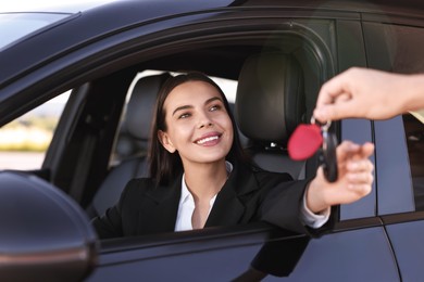 Photo of Happy young woman getting key inside her new car