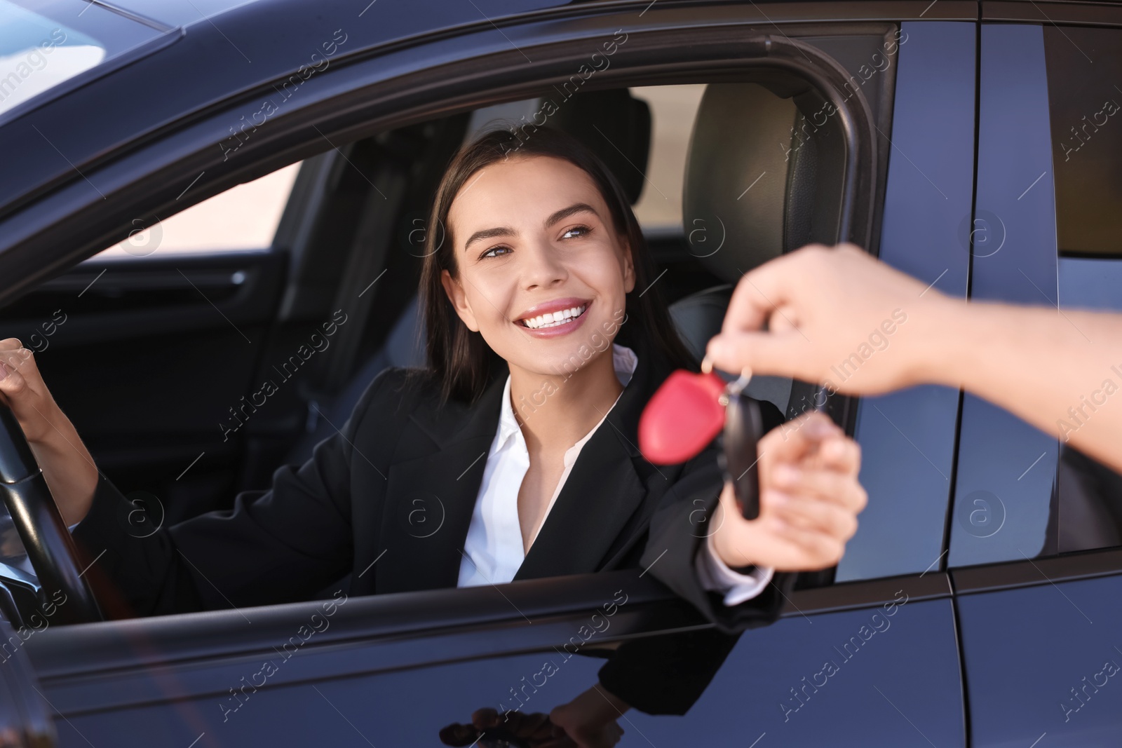 Photo of Happy young woman getting key inside her new car