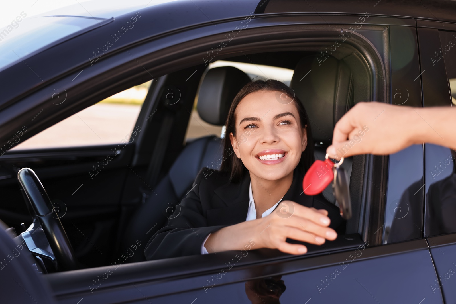 Photo of Happy young woman getting key inside her new car