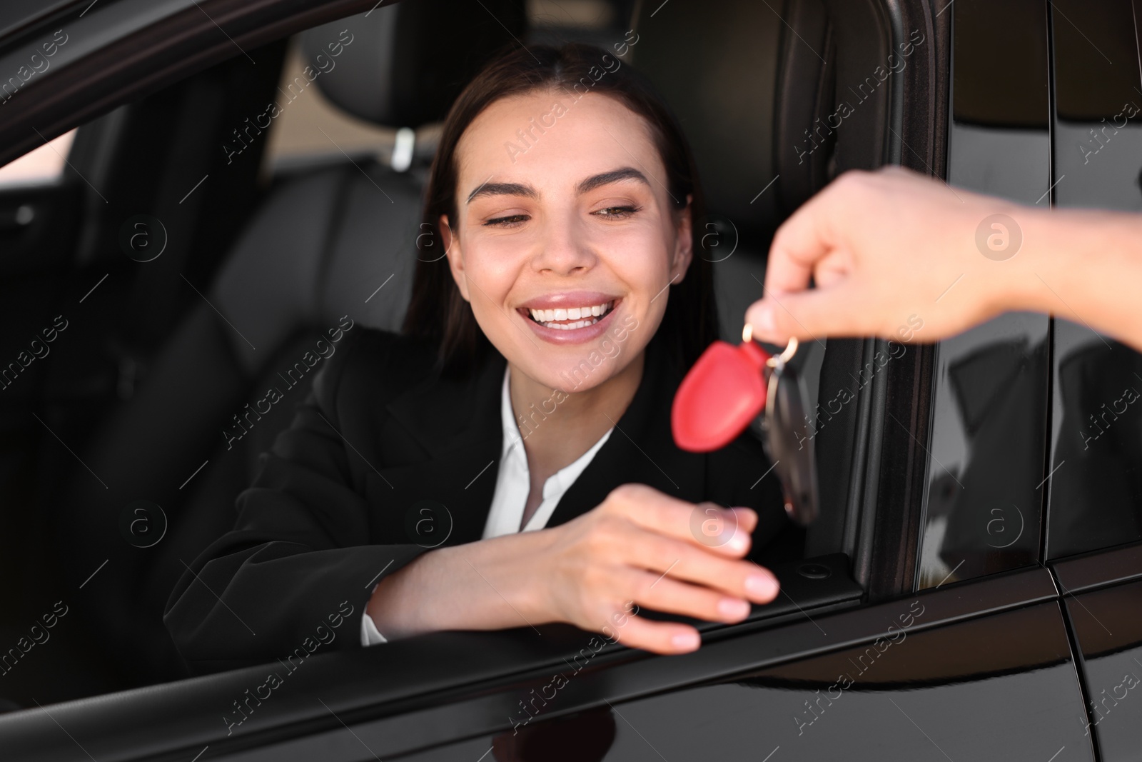 Photo of Happy young woman getting key inside her new car