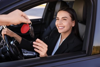 Photo of Happy young woman getting key inside her new car