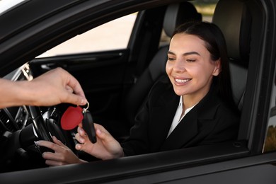 Photo of Happy young woman getting key inside her new car