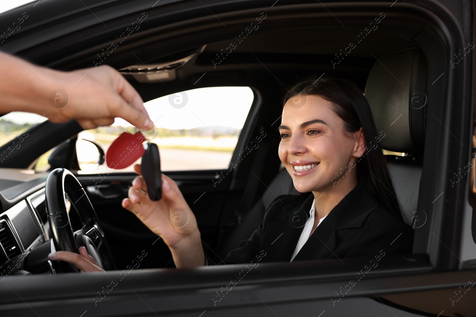 Photo of Happy young woman getting key inside her new car