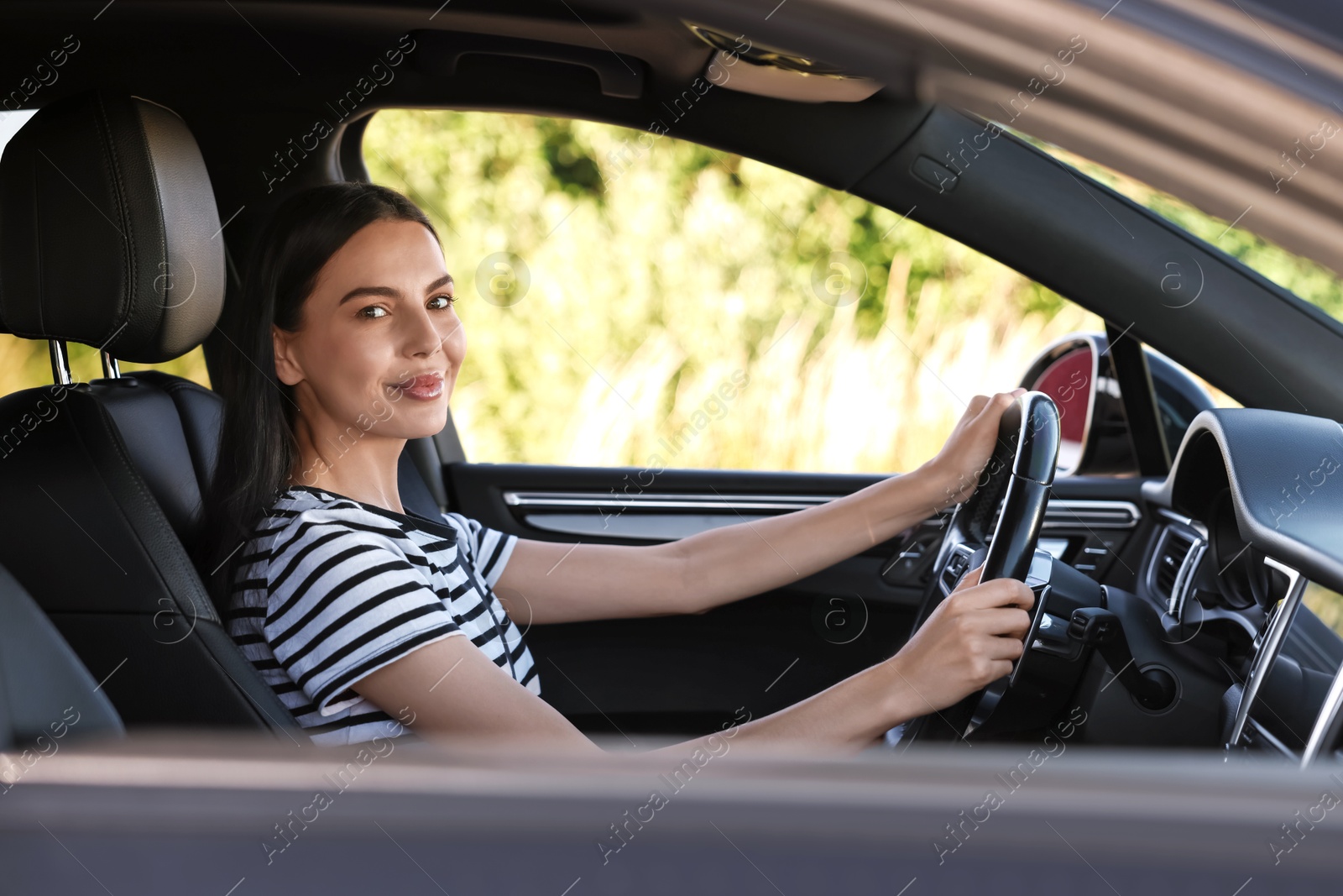 Photo of Beautiful young woman holding steering wheel while driving car, view from outside