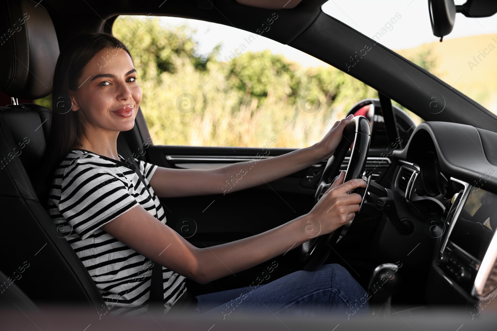 Photo of Beautiful young woman holding steering wheel while driving car, view from outside