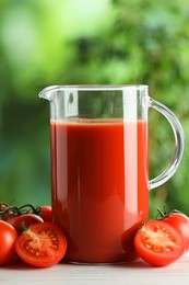 Photo of Tasty tomato juice in glass jug and fresh vegetables on white table outdoors