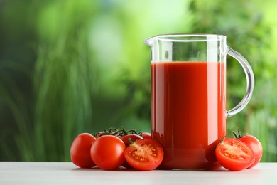 Photo of Tasty tomato juice in glass jug and fresh vegetables on white table outdoors. Space for text