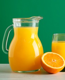 Photo of Tasty orange juice and fresh fruit on white wooden table