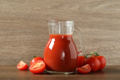 Photo of Tasty tomato juice in jug and vegetables on wooden table