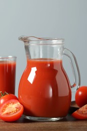 Photo of Tasty tomato juice in jug, glass and vegetables on wooden table, closeup