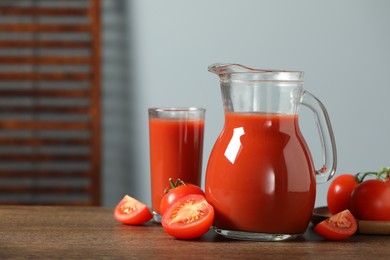 Photo of Tasty tomato juice in jug, glass and vegetables on wooden table. Space for text