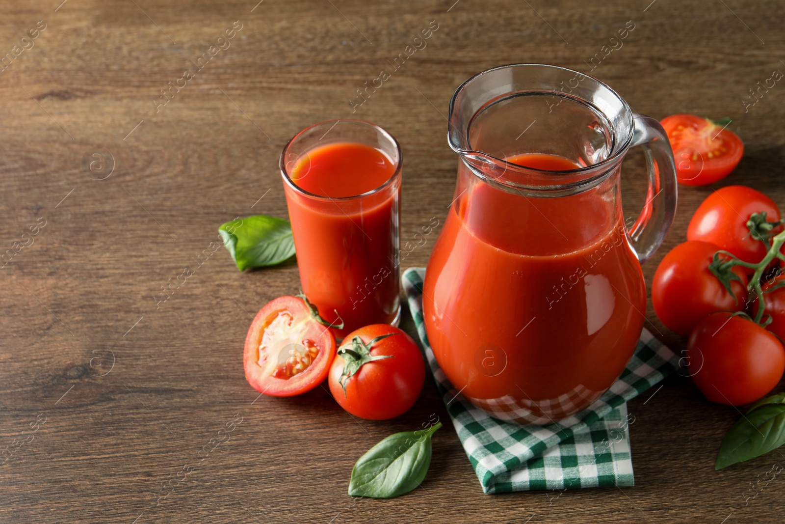 Photo of Tasty tomato juice in jug, glass and vegetables on wooden table. Space for text