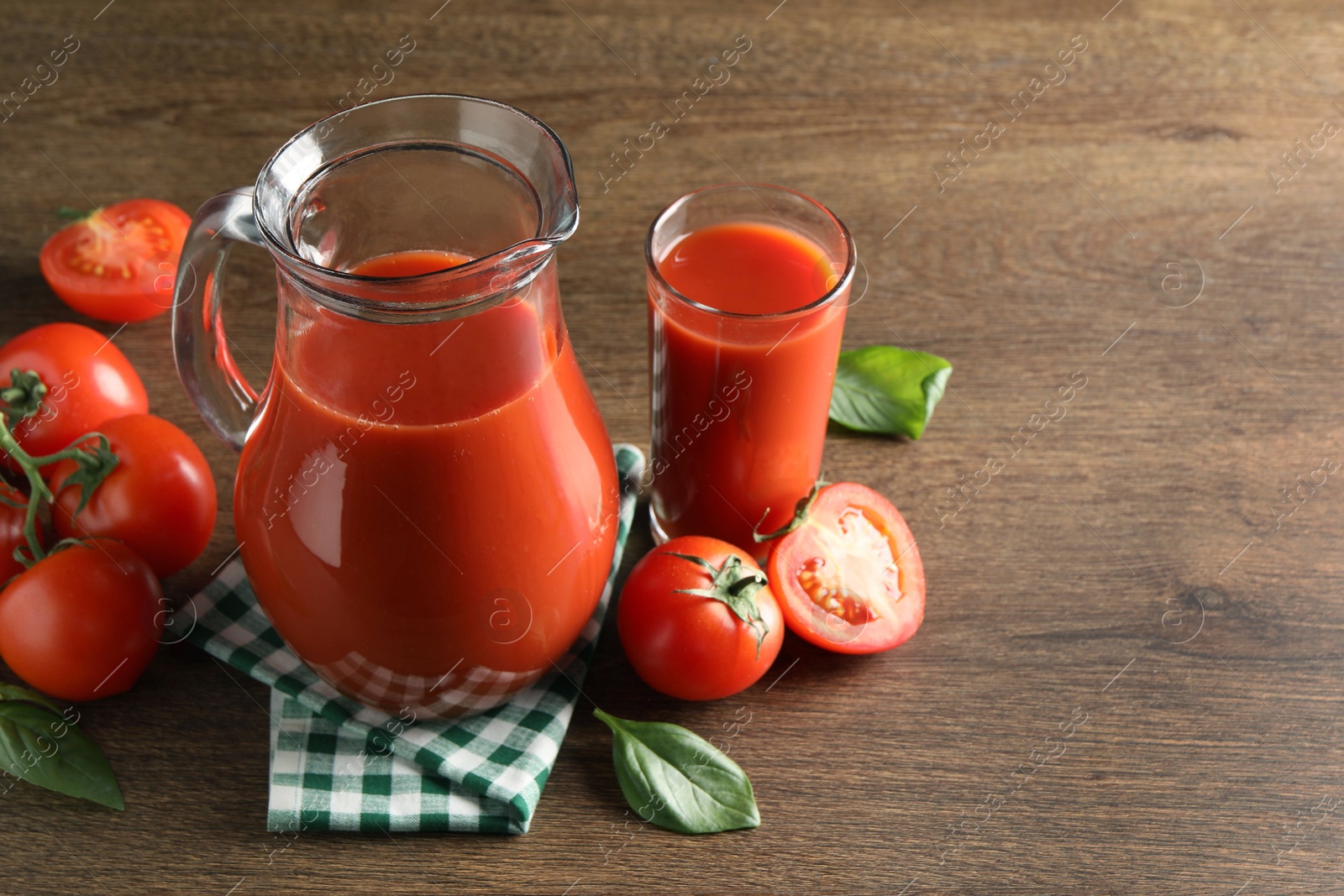 Photo of Tasty tomato juice in jug, glass and vegetables on wooden table. Space for text