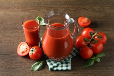 Photo of Tasty tomato juice in jug, glass and vegetables on wooden table