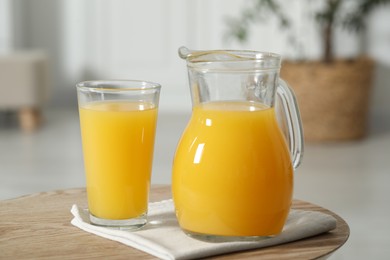 Photo of Tasty orange juice in jug and glass on wooden table, closeup