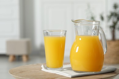 Photo of Tasty orange juice in jug and glass on wooden table. Space for text