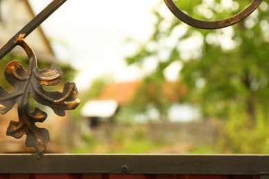 Photo of Cobweb on wrought iron fence scrolls outdoors, closeup