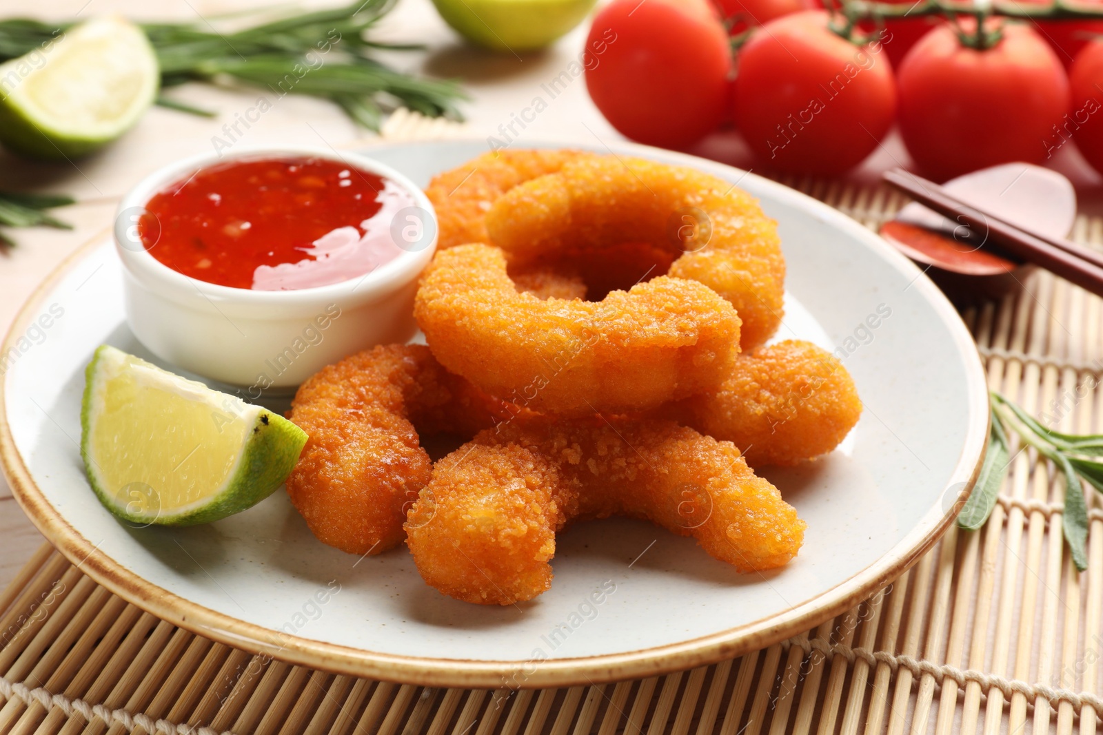 Photo of Tasty breaded fried shrimps served with lime and sauce on table, closeup