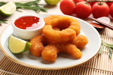 Tasty breaded fried shrimps served with lime and sauce on table, closeup